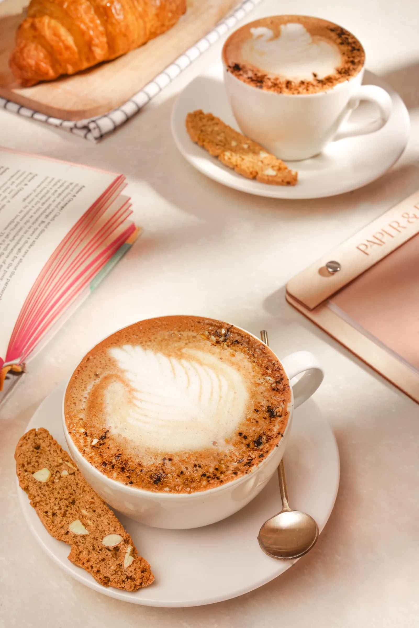 A latte with leaf art beside an open book