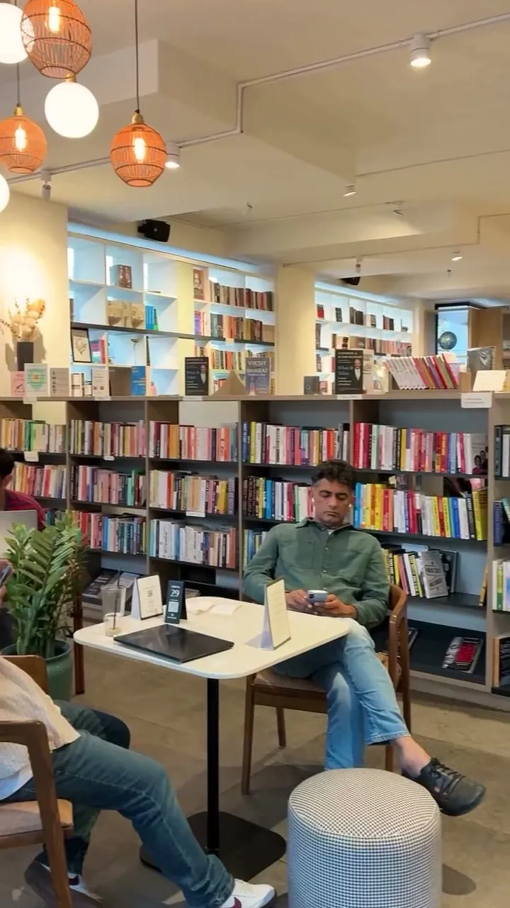 A reader at a café table among the shelves of Ink & Oak Bookstore, Paper & Pie HSR