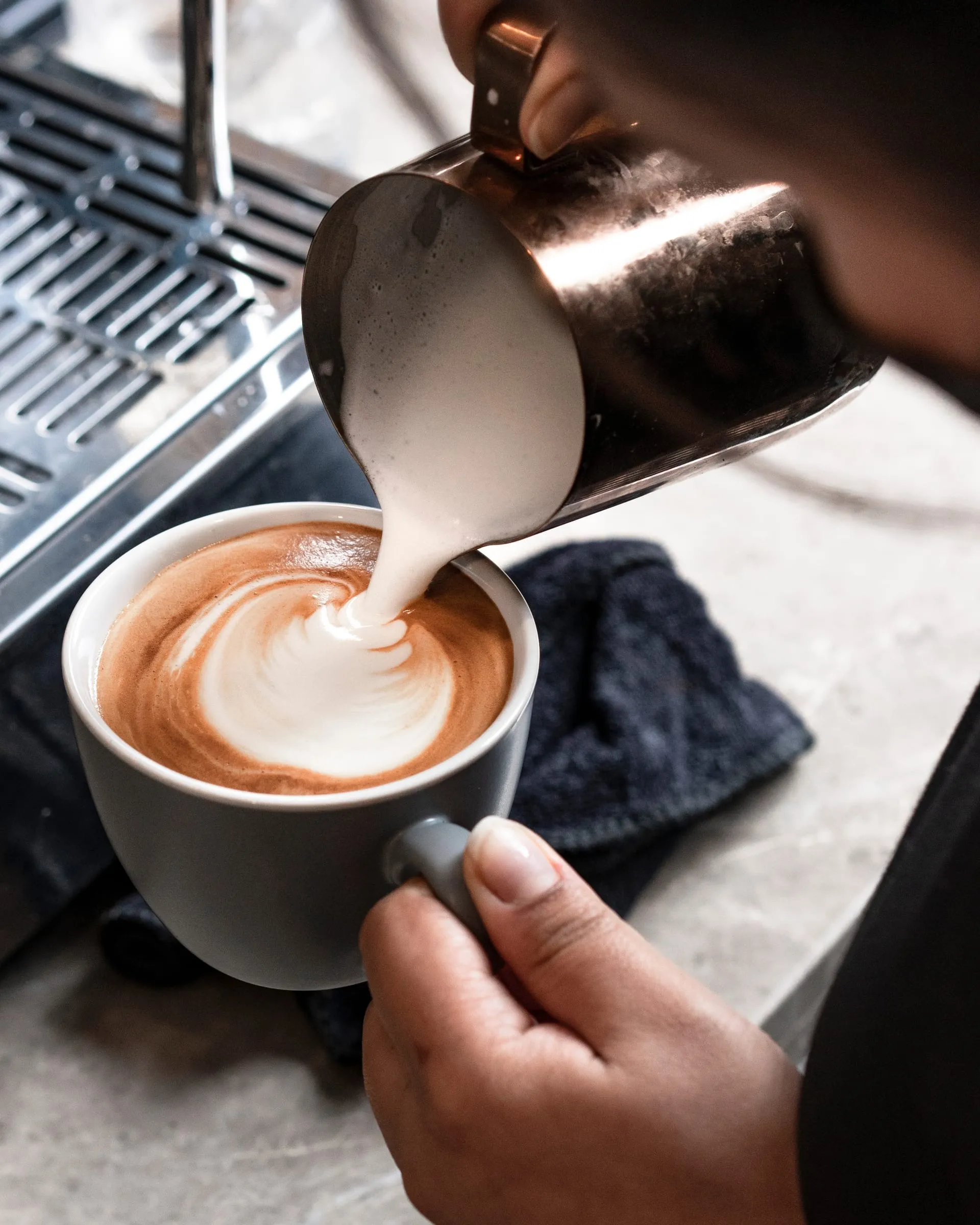 A barista pouring latte art into a cup